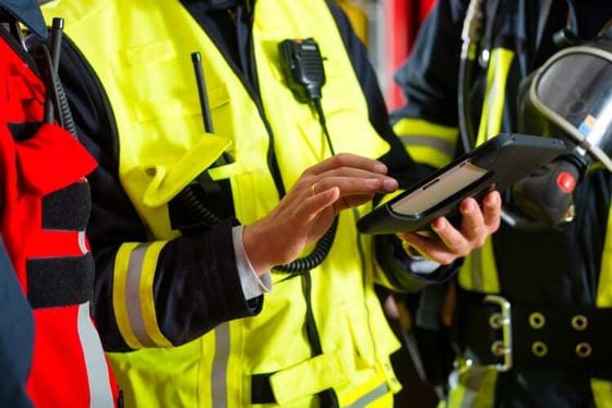 Firefighter wearing PPE gear and performing equipment checks on a device.
